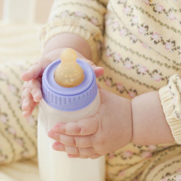 Mixed race baby girl holding bottle