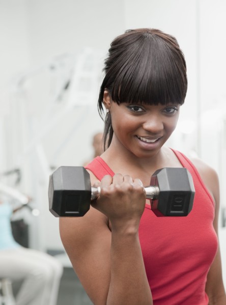 African woman using hand weight in health club