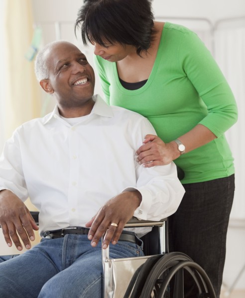 African woman pushing husband in wheelchair