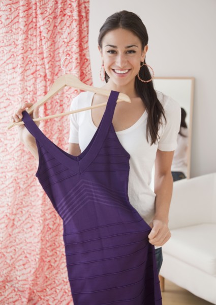 Hispanic woman holding dress at store
