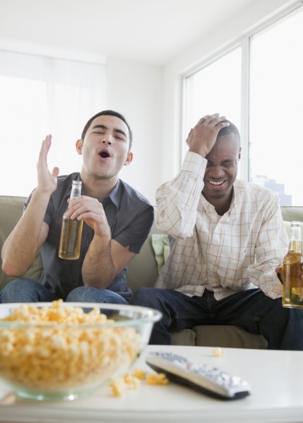 Men drinking beer and watching sports on television