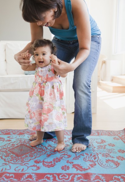 Hispanic mother helping daughter learn to walk