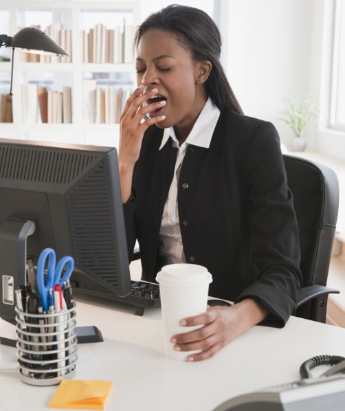 Mixed race businesswoman yawning at desk