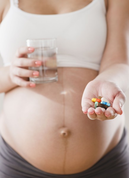 Pregnant Hispanic woman with handful of pills