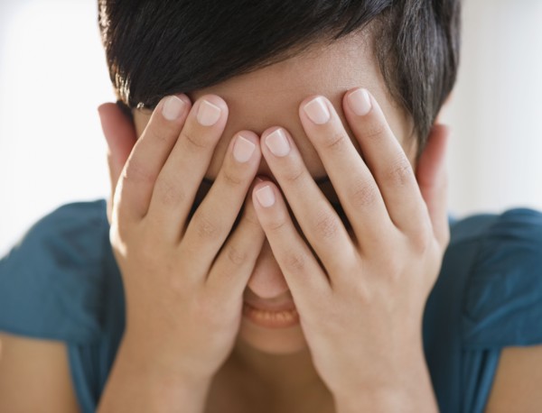 Mixed race woman covering face with hands