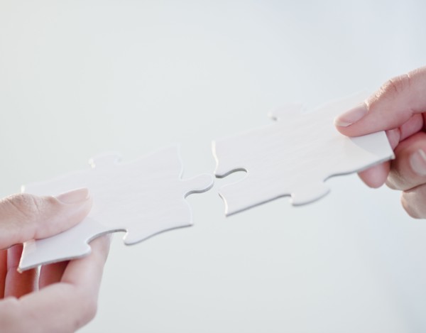 Hands connecting jigsaw puzzle pieces