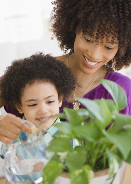 Mother and daughter watering potted plant