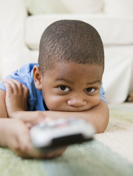 African American boy laying on floor watching television