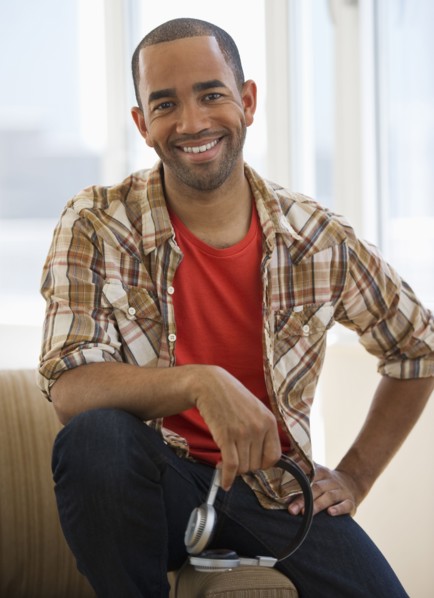 Mixed race man sitting on sofa holding headphones