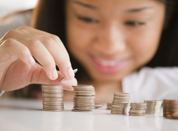 Close up of mixed race teenage girl stacking coins