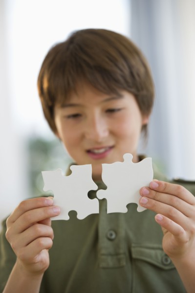 Mixed race boy connecting jigsaw pieces