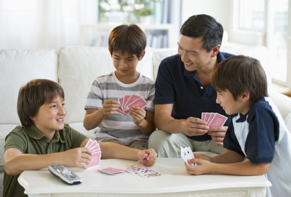 Father and sons playing cards in living room