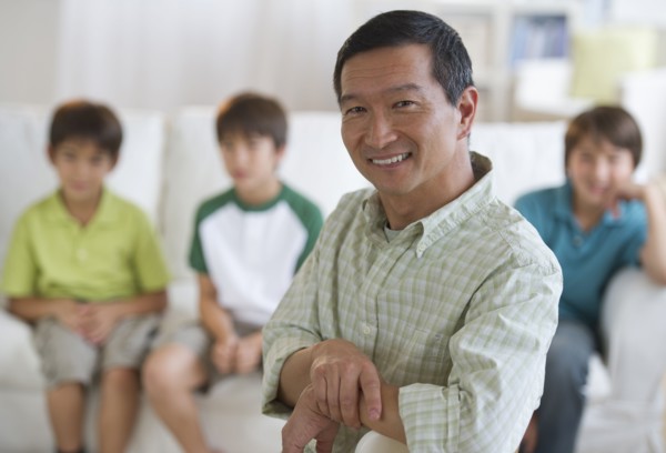 Smiling father in living room with sons in background