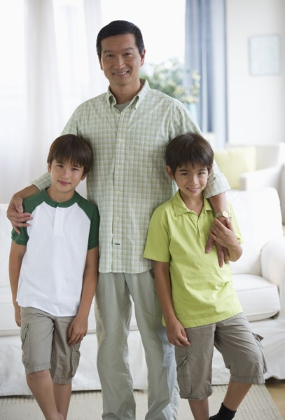 Smiling father and twin sons in living room