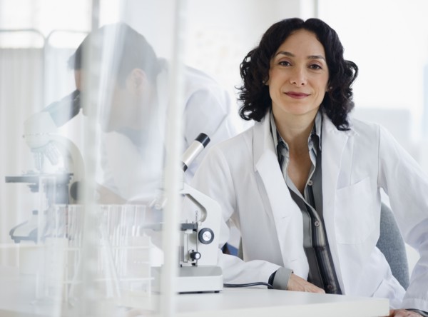 Hispanic researcher in laboratory next to microscope