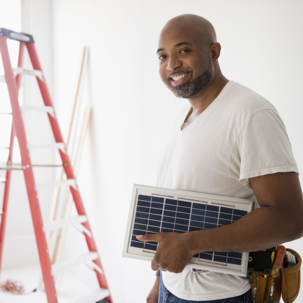 African American construction worker carrying solar panel
