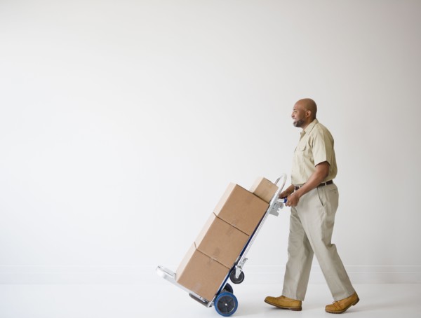 African American deliveryman pushing hand truck with boxes