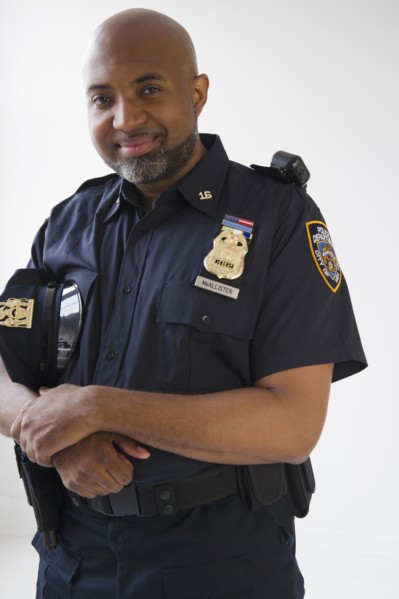 Smiling African American policeman holding cap