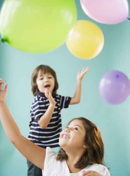 Hispanic brothers and sisters playing with balloons