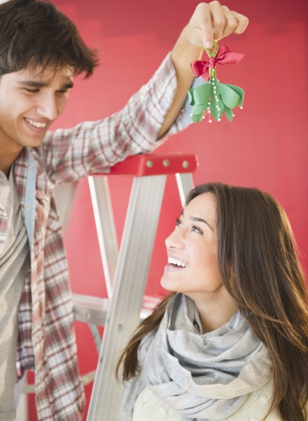 Man holding mistletoe over wife's head