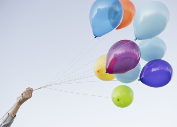 Caucasian woman holding bunch of balloons