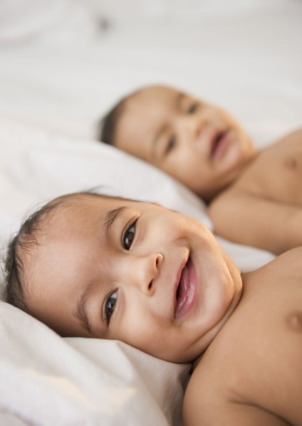 Smiling mixed race twins laying together