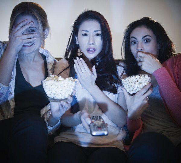 Friends eating popcorn and watching television