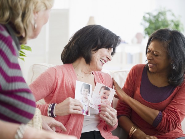 Woman showing friends photographs of her grandchildren