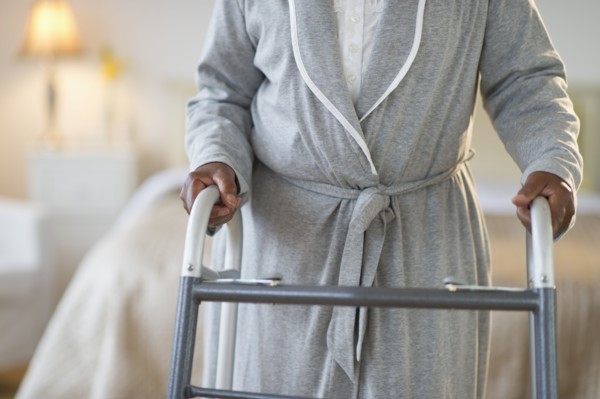 Black woman walking with walker in bedroom