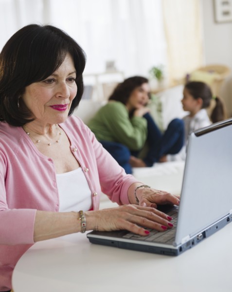 Woman using laptop with family in background