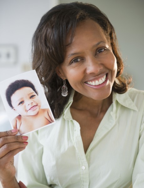 Black woman holding photograph of baby