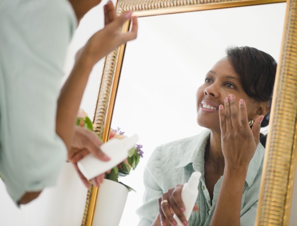 Black woman applying moisturizer