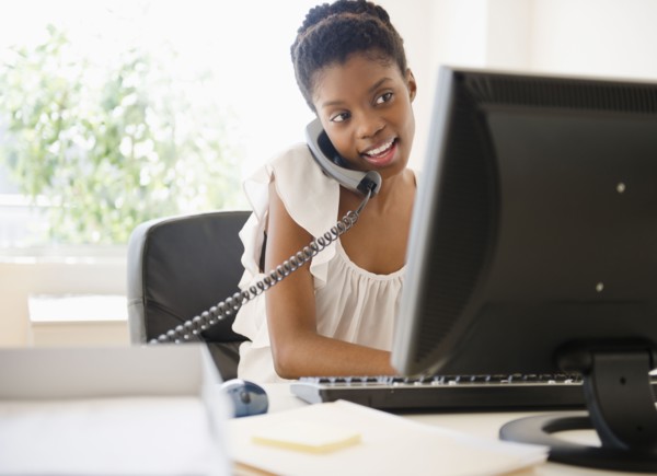 Black businesswoman talking on phone and using laptop