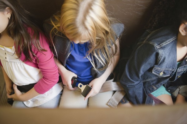 Children buckling seat belts on school bus