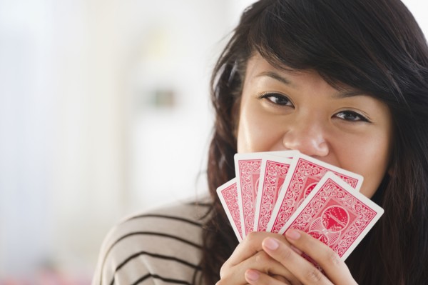 Pacific Islander woman covering her mouth with playing cards