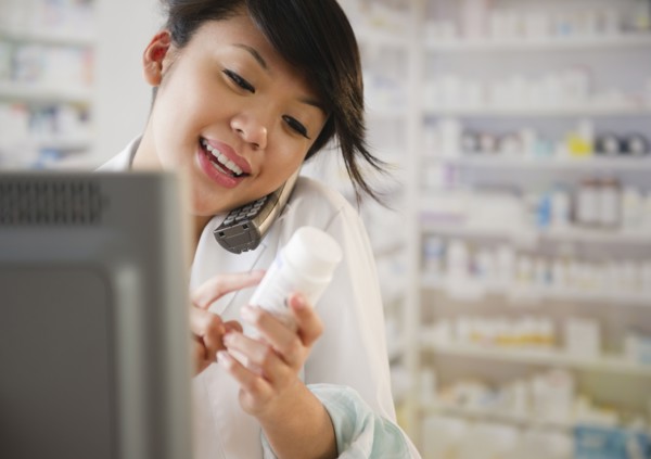 Pacific Islander pharmacist reviewing medication and talking on telephone