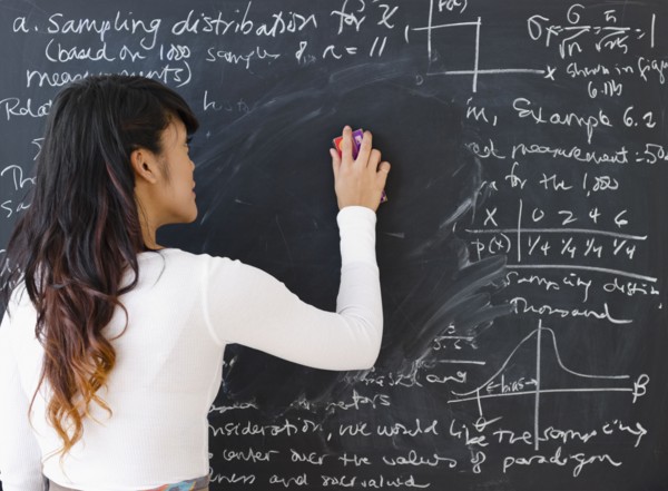 Pacific Islander teacher erasing math from blackboard