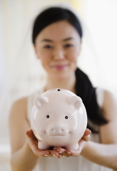 Japanese bride holding piggy bank