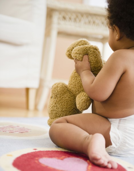 Black baby girl holding teddy bear