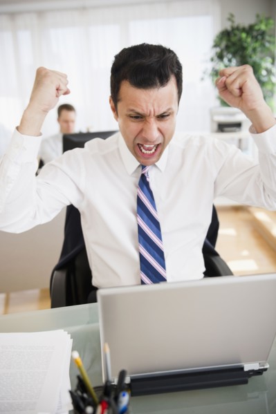 Angry mixed race businessman shouting in laptop