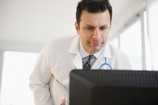 Mixed race doctor looking at computer monitor