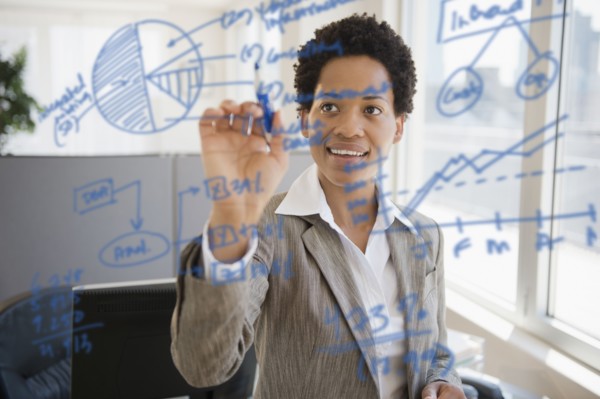 African American businesswoman writing on glass board
