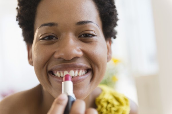 African American woman putting on lipstick