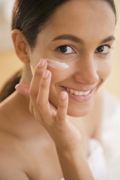 Hispanic teenager putting on face lotion