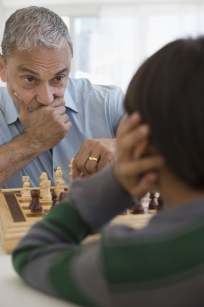 Hispanic grandfather and grandson playing chess