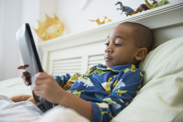 African American boy using tablet computer in bed
