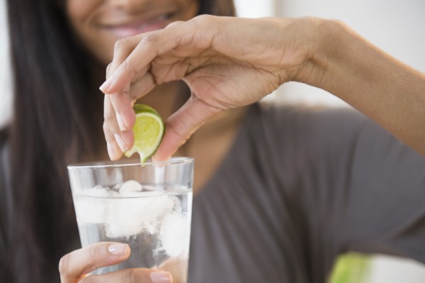 Mixed race woman squeezing lime into drink