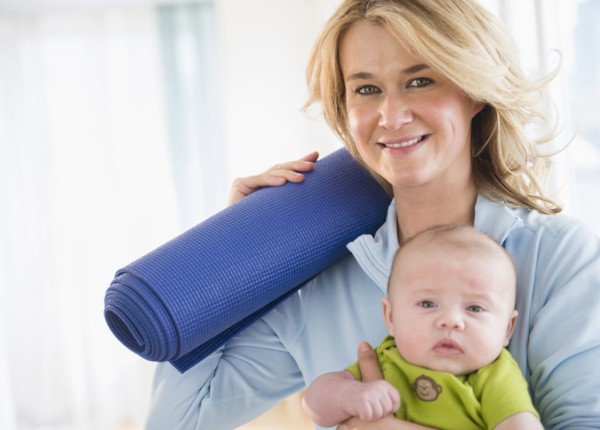Caucasian mother with baby holding yoga mat