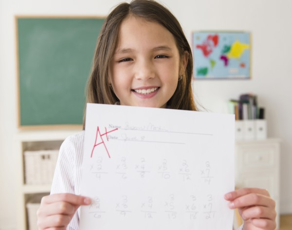 Mixed race girl holding paper with A+ grade