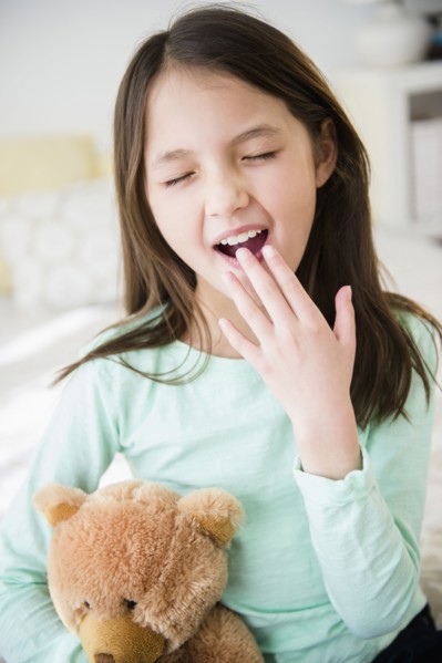 Mixed race girl with teddy bear yawning